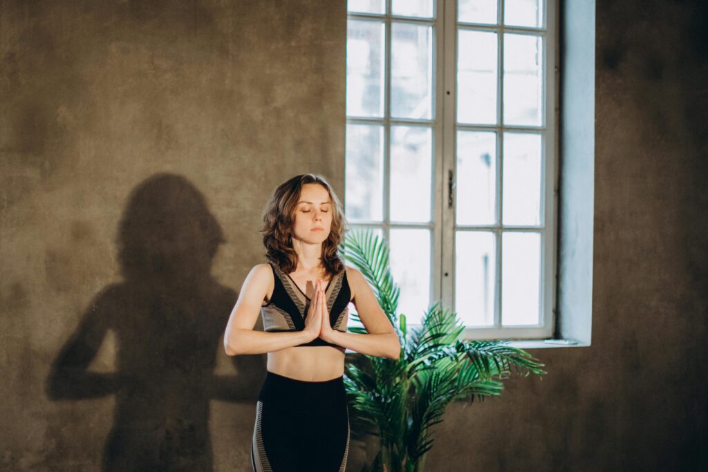 A calm woman practicing yoga in a serene indoor setting, focusing on mindfulness and relaxation.